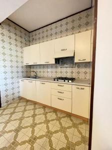 una cucina con armadietti bianchi e pavimento piastrellato di ARISTON - WALTERIGATO Apartments SOLO PER FAMIGLIE a Lido di Jesolo