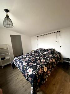 1 dormitorio con 1 cama con colcha de flores en Appartement COSY en Sartilly