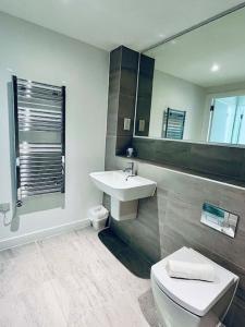 een badkamer met een wastafel, een toilet en een spiegel bij Old Trafford: Self-Serviced One Bedroom Apartment in Manchester