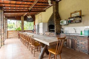 una grande cucina con un lungo tavolo in legno e sedie di chácara paraíso tropical a Biritiba-Mirim