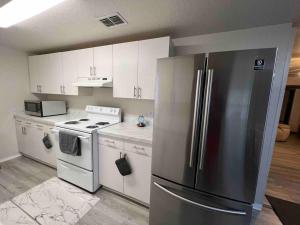 a kitchen with white cabinets and a stainless steel refrigerator at Home in Kissimmee with Huge Backyard in Kissimmee