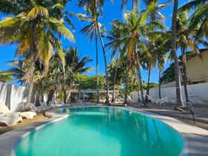 a swimming pool with palm trees and lounge chairs at Sunset Surf Villa in La Libertad