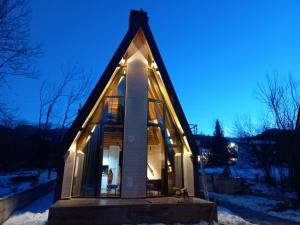 a glass house with a triangular roof in the snow at Villa Tina in Štrpce