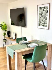 a dining room table with green chairs and a television at Stilvolles Wohnen am Hafen in Bregenz