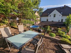 una mesa y sillas en un patio con una casa en Urlaubsmagie - Helle Wohnung mit Garten & Pool - R3 en Rathmannsdorf