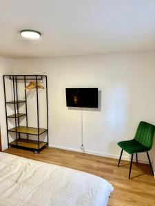 a bedroom with a green chair and a tv on the wall at Stilvolles Wohnen am Hafen in Bregenz