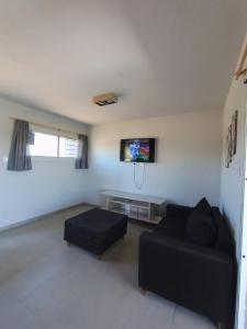 a living room with a black couch and a flat screen tv at Casa Estancia Vieja in Cordoba