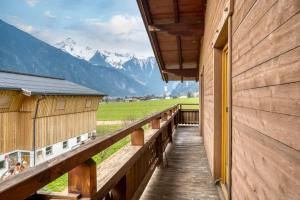 un porche de madera en una casa con montañas al fondo en Adventure Holiday Hub: Gartenhäusl en Mayrhofen