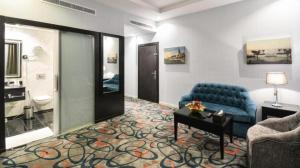 un salon avec un canapé bleu et une salle de bains. dans l'établissement فندق الراحة السويسرية, à Djeddah