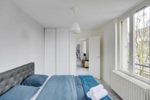 a bedroom with a bed with blue sheets and a window at Chic and spacious apart with parking in Cergy