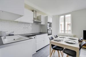 a kitchen with white cabinets and a table with chairs at Chic and spacious apart with parking in Cergy