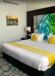 una habitación de hotel con una cama grande con almohadas amarillas en فندق الراحة السويسرية en Yeda