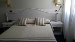 una camera con un letto bianco con due comodini di Hotel Villa Tiziana a Lido di Venezia