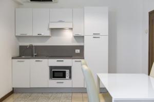 una cucina bianca con lavandino e forno a microonde di Residence Oasi a Limone sul Garda