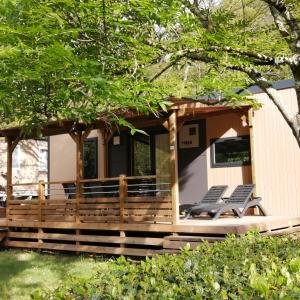 a cabin with a porch with two lounge chairs at Camping Le Ventadour in Meyras