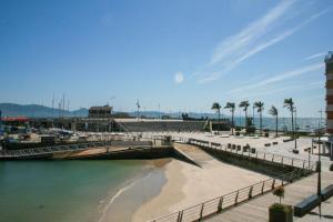 una playa con un muelle, palmeras y el océano en Apartamento con excelente localización y vistas al mar, en Sanxenxo