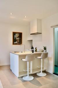 a kitchen with a sink and two bar stools at Anna Boutique Apartments in Nijmegen