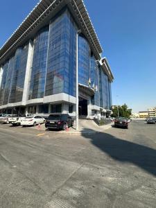 ein großes Gebäude mit Autos auf einem Parkplatz in der Unterkunft فندق الراحة السويسرية in Dschidda