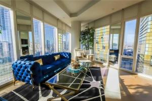 a living room with a blue couch and large windows at Elegant Corner 2 Bedroom Condo with Floor to Ceiling Windows in Las Vegas