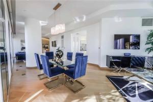 a dining room with a glass table and blue chairs at Elegant Corner 2 Bedroom Condo with Floor to Ceiling Windows in Las Vegas