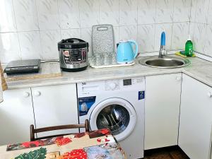 een aanrecht met een wasmachine en een wastafel bij Apartment Seifullina473 in Alma-Ata
