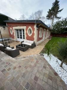 a brick house with a patio with couches at Maison de charme dans un écrin de verdure - Le Vésinet - 15mns de Paris in Le Vésinet