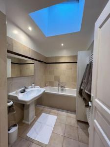 a bathroom with a sink and a bath tub with a skylight at Maison de charme dans un écrin de verdure - Le Vésinet - 15mns de Paris in Le Vésinet