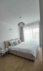 a white bedroom with a large bed and a chandelier at Oak Apartment lovely one bedroom apartment at Columna Residence near Vivo mall in Cluj-Napoca