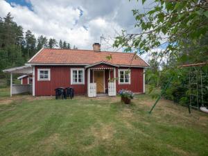 une maison rouge avec une terrasse couverte et des chaises dans une cour dans l'établissement Högerödja, à Hultsfred