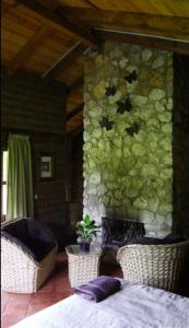 a room with two chairs and a stone wall at La Tierra Grande in Zacatlán