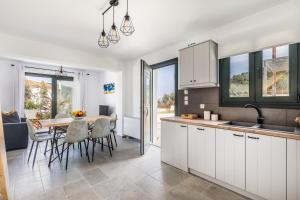 a kitchen with white cabinets and a table with chairs at Marani Villas Collection in Skopelos Town +88 photos