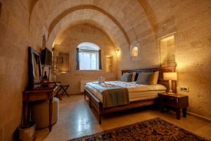 a bedroom with a large bed in a stone room at Misty Cave Hotel in Urgup