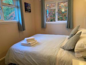 1 dormitorio con 1 cama blanca y 3 toallas en Burnside Chalet on Reelig Estate Near Inverness, en Kirkhill