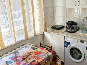 een keuken met een wasmachine en een tafel bij Apartment Seifullina473 in Alma-Ata