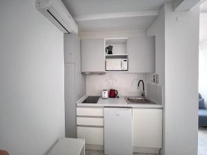 een kleine keuken met witte kasten en een wastafel bij Luceros 310 New in Alicante
