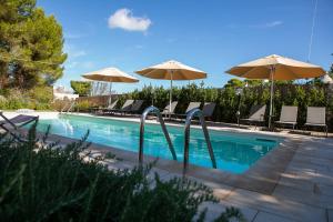 einen Pool mit Sonnenschirmen und Stühlen sowie einen Pool in der Unterkunft Angolo di Puglia in Locorotondo