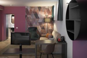 a living room with a tv and a table and chairs at Hotel all'Azzurro in Limone sul Garda