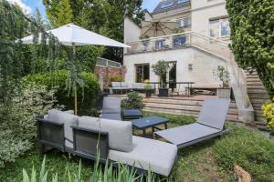 um quintal com cadeiras e um guarda-sol e uma casa em Villa des Oliviers em Fontenay-sous-Bois