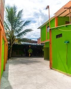 een groen en oranje gebouw met een palmboom in de verte bij Hotel California Tropical in La Tebaida