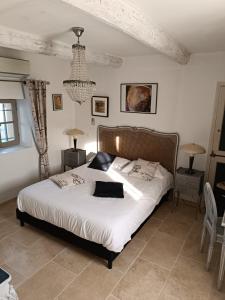 マロセーヌにあるMas de Longuefeuilleのベッドルーム1室(白いシーツとシャンデリア付)