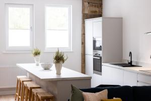 a kitchen with white cabinets and a table with chairs at The Wagon Shed Stylish Conversion with Garden and Parking in Sowerby Bridge