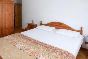 een slaapkamer met een wit bed en een houten hoofdeinde bij Residence Malibu Appartamento 2 in Falcade
