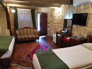 a bedroom with two beds and a chair and a television at CAPPADOCIA PALACE HOTEL in Nevşehir