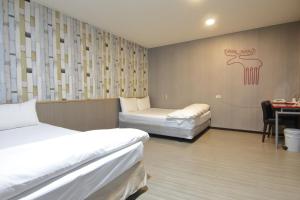 a room with two beds and a table with a desk at Baoshan Hotel in Zhongli