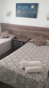 a bedroom with two beds and a painting on the wall at HOTEL ROMA DE TANDIL in Tandil