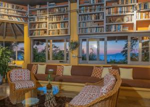 biblioteca con sofá, sillas y libros en Beachfront Summer Villa, en Puerto Vallarta