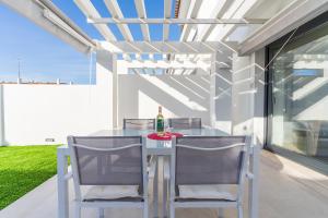 厄爾－汝姆披多的住宿－Pareado con piscina en el Rompido，餐桌、两把椅子和一瓶葡萄酒