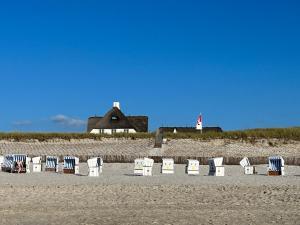 a row of chairs on a beach with a lighthouse at Lüttes Tohuus in Tinnum