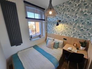 a bedroom with a bed and a desk and a window at Ottimo Apartamenty Długa in Bydgoszcz