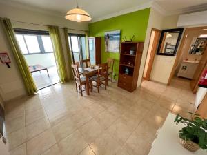 ein Wohnzimmer mit grünen Wänden sowie einem Tisch und Stühlen in der Unterkunft T1s Portimão - Center in Portimão